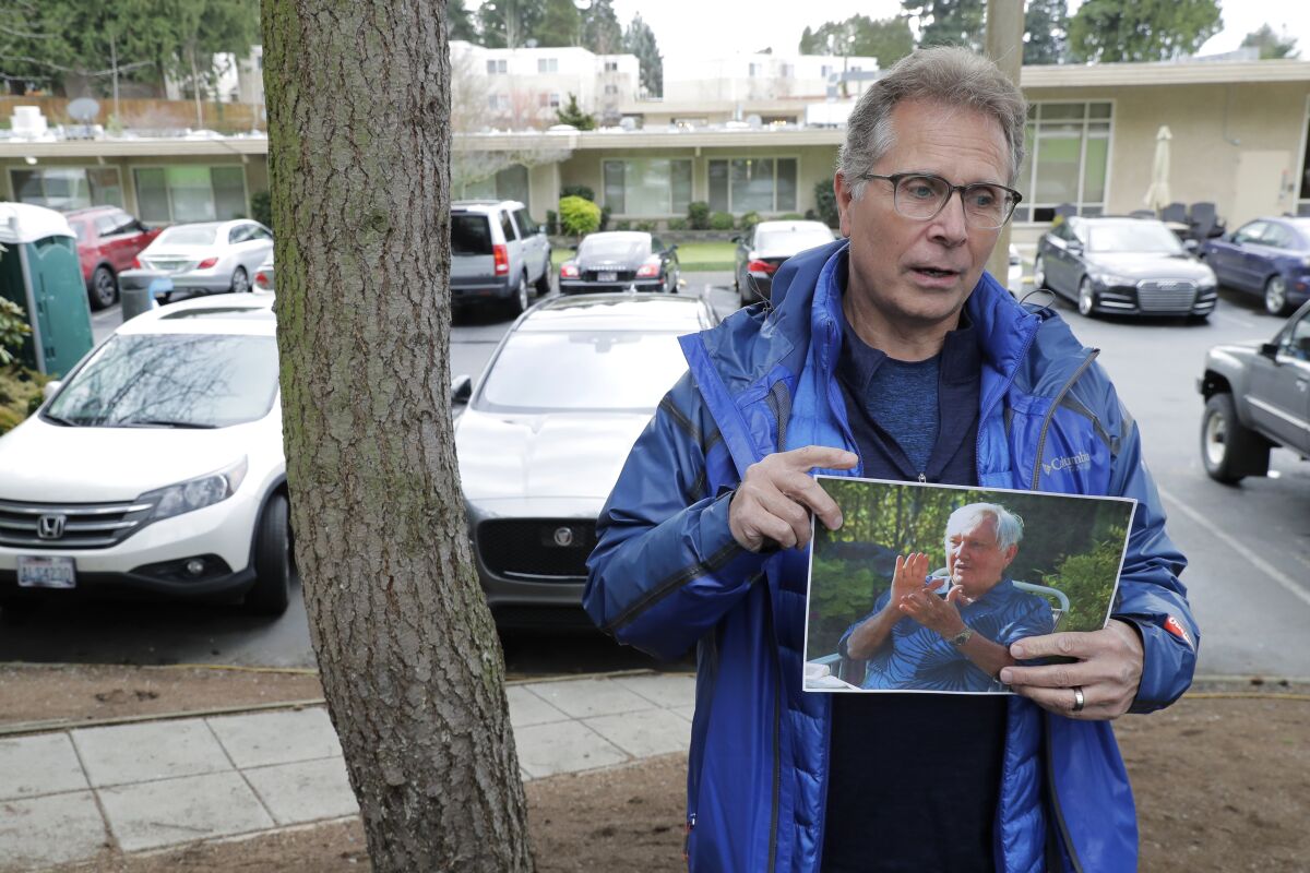 In this March file photo, Scott Sedlacek poses while holding a picture of his father, Chuck. Both men battled COVID-19.