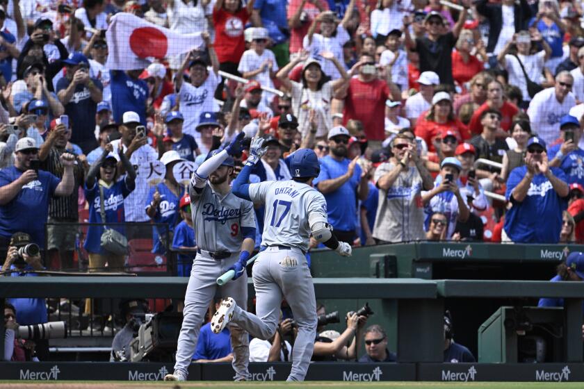 Dodger Shohei Ohtani high-fives Gavin Lux after hitting a home run against the St. Louis Cardinals Sunday