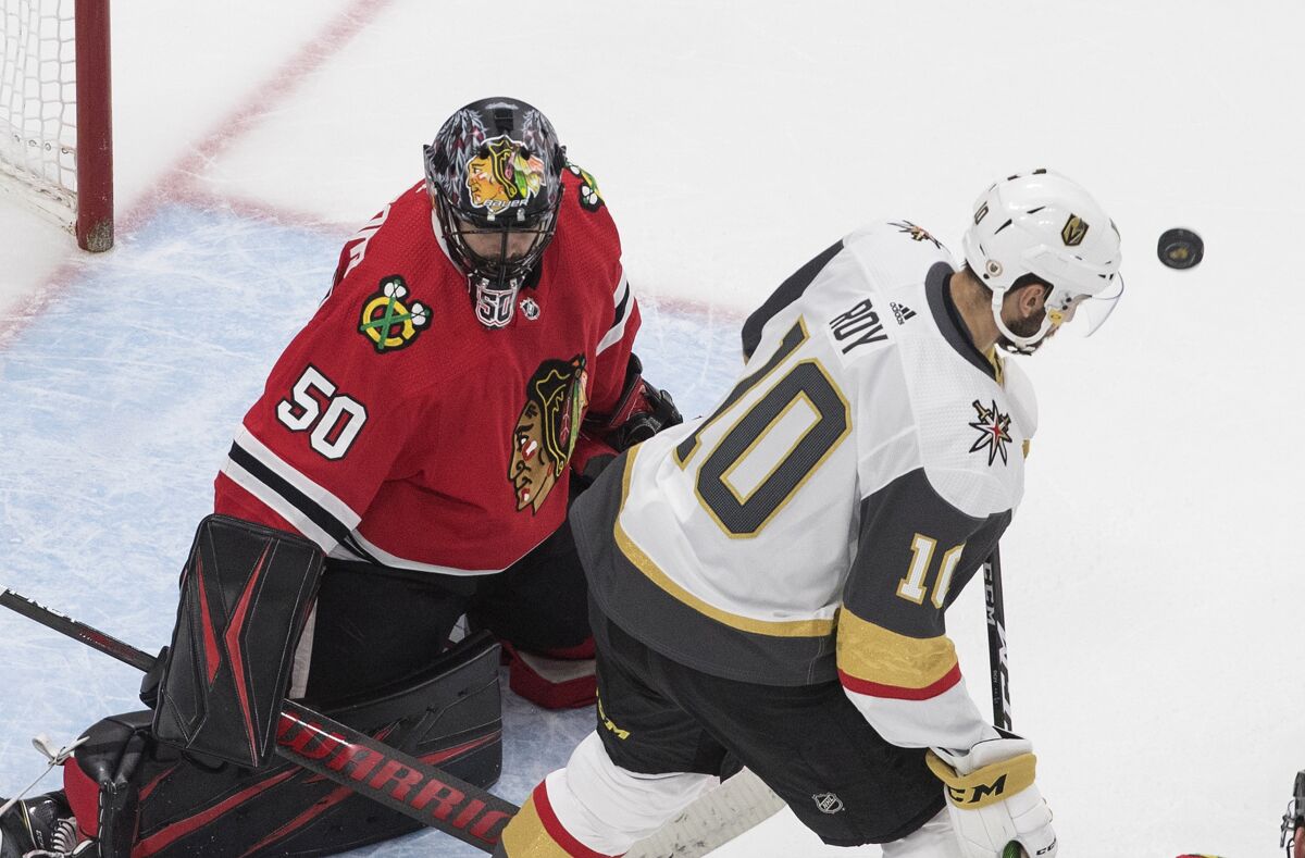 Vegas Golden Knights' Nicolas Roy (10) looks for the rebound off Chicago Blackhawks goalie Corey Crawford (50) during the third period in Game 4 of an NHL hockey first-round playoff series Sunday, Aug. 16, 2020, in Edmonton, Alberta. (Jason Franson/The Canadian Press via AP)