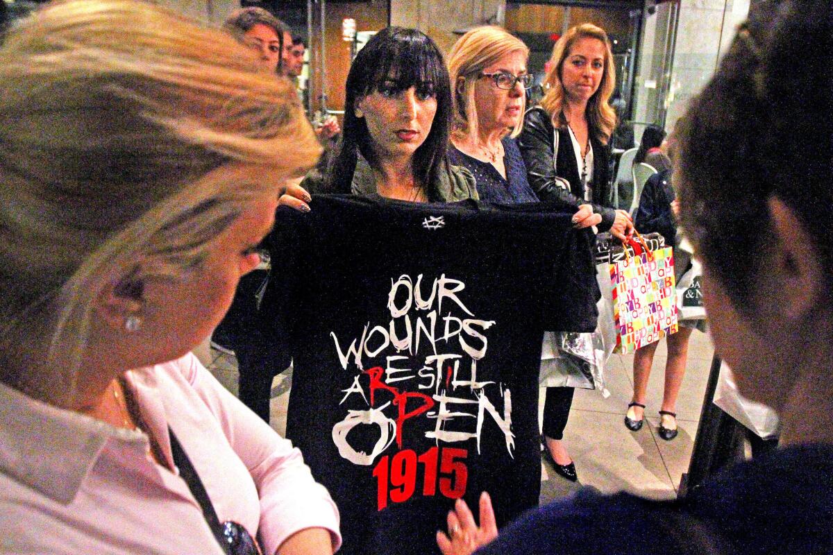 Elin Nazarian, who works at Shop1915.com, holds up a t-shirt for a prospective buyer at the Americana at Brand in Glendale on Friday, March 13, 2015. The kiosk retail store Shop1915.com was banned from displaying or selling t-shirts recognizing the 100th anniversary of the Armenian Genocide. After receiving criticism, the outdoor mall's management rescinded the ban.
