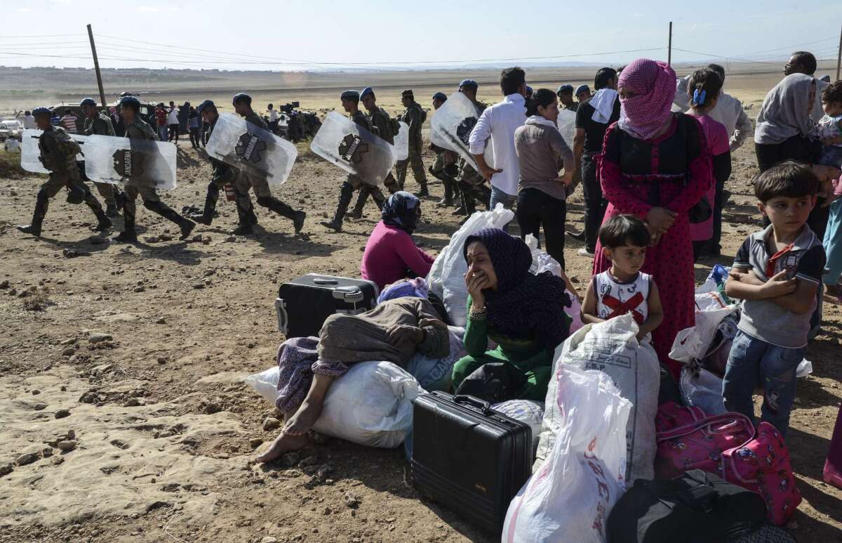 Syrian Kurds rest after crossing the border between Syria and Turkey on Oct. 11. 