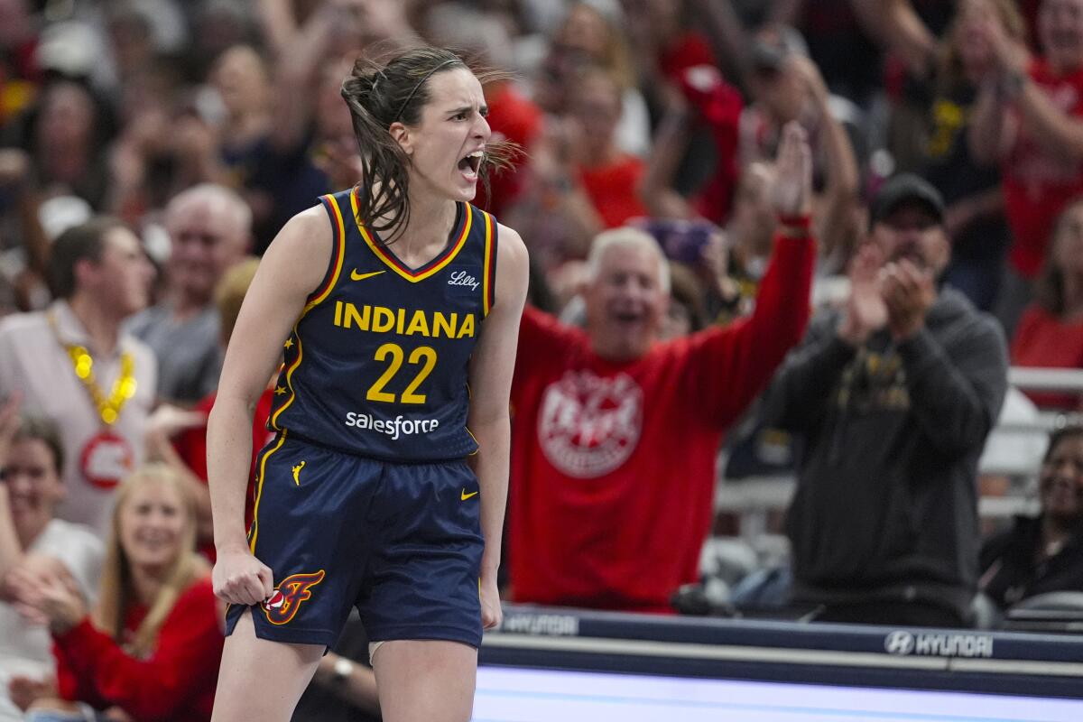 Indiana Fever guard Caitlin Clark yells in celebration after a three-point basket, with fans cheering in the background