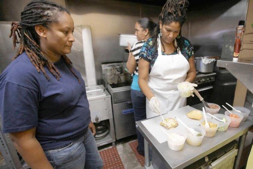 Ella's Belizean Restaurant offers takeout boxes of panades, salbutes and garnaches. Here owner Carla Dawson supervises the cooking of sister Connie.