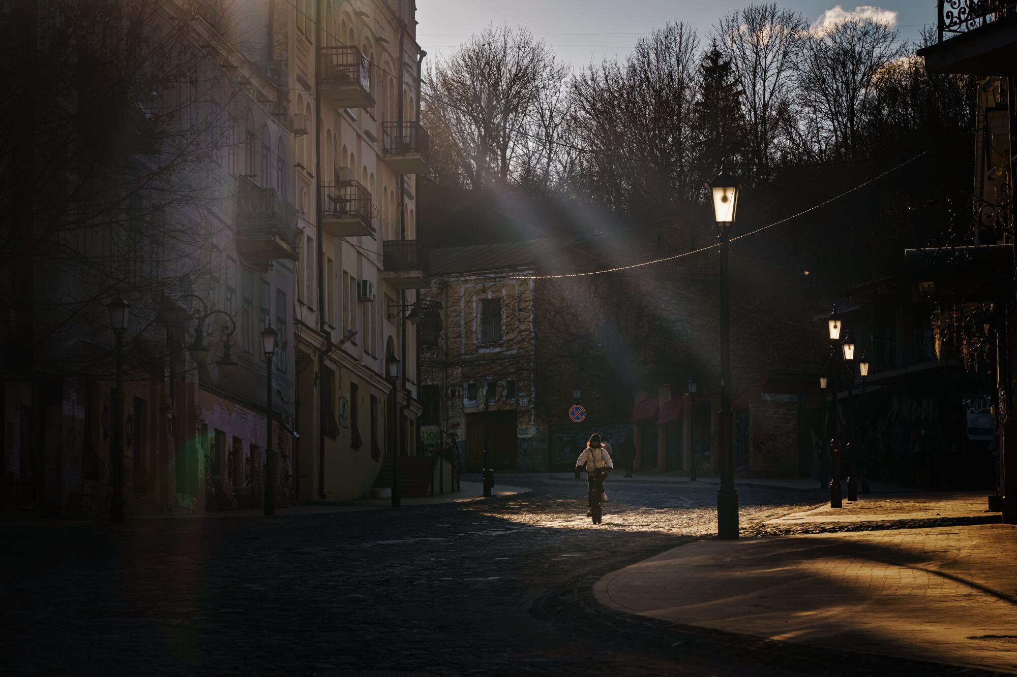 A woman cycles in the Podil neighborhood in Kyiv, Ukraine