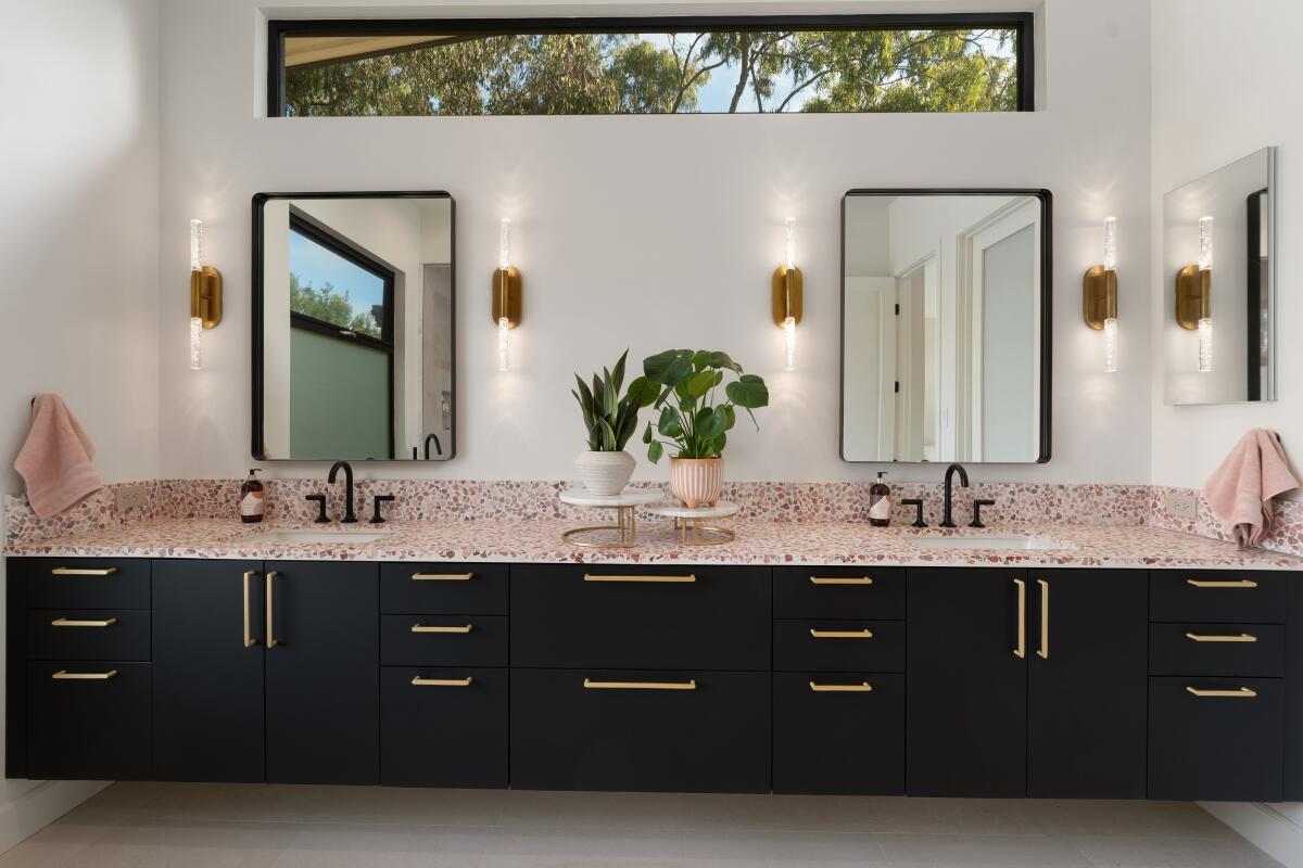 Plants add touches of color and life to a large modern bathroom with dark cabinets and quartz counters.