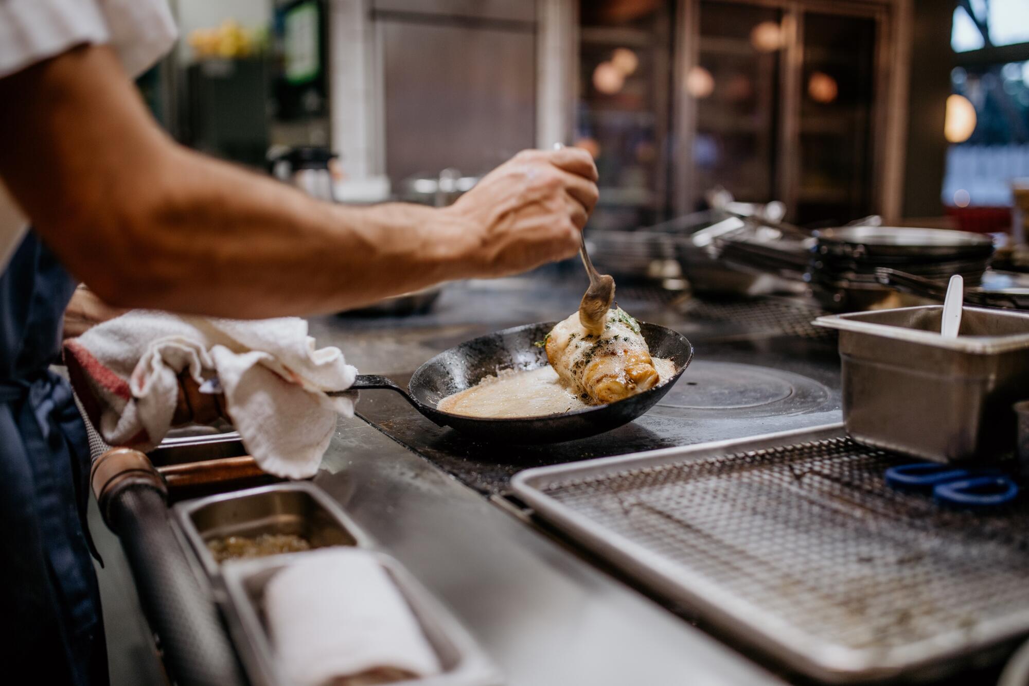 Chef Eric Bost baste roasted monkfish with browned butter