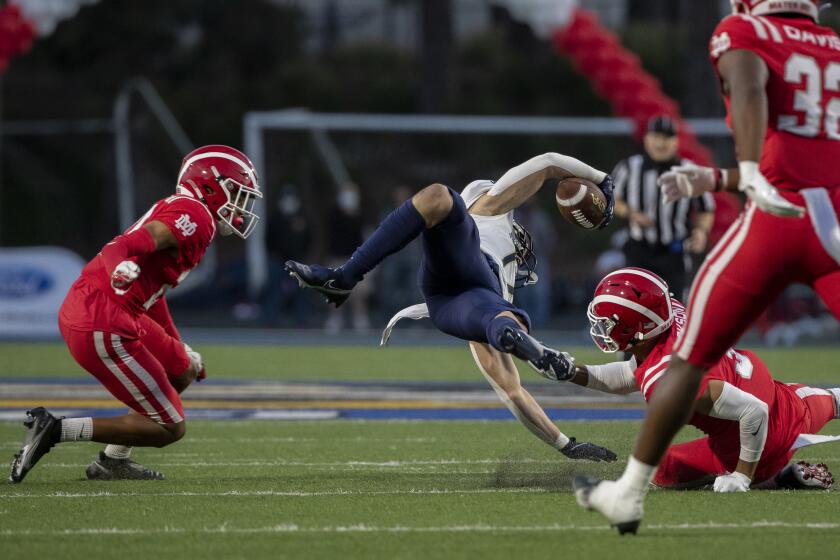 SANTA ANA, CA - APRIL 17, 2021: St John Bosco wide receiver is expended by Mater Dei Kassius Ashtani, left, and Domani Jackson in the first half at Santa Ana Stadium on April 17, 2021 in Santa Ana California.(Gina Ferazzi / Los Angeles Times)
