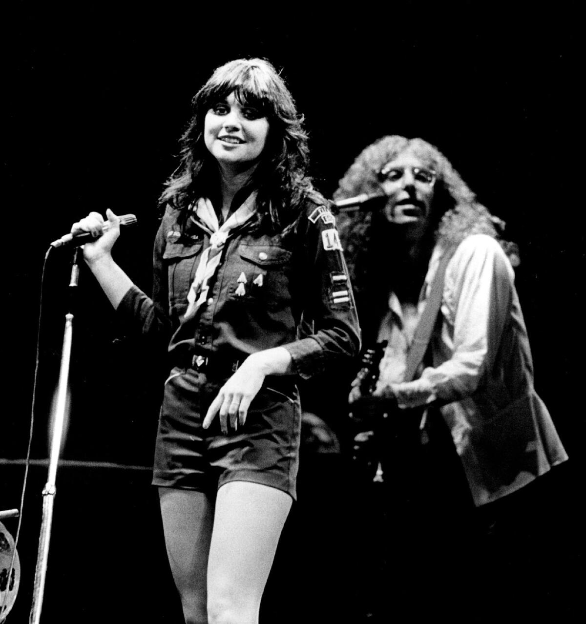 Black and white photo of Linda Ronstadt performing with guitarist Waddy Wachtel behind her