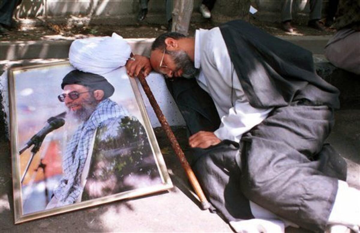 FILE-In this Tuesday, August 8, 2000 file photo, Iranian clergyman Mohammad Azadparvar, who allegedly was injured by chemical weapons in the 1980-88 Iran-Iraq war, rests next to a picture of the supreme leader Ayatollah Ali Khamenei, at a demonstration in front of Iranian parliament in support of the supreme leader Ayatollah Ali Khamenei. For more than a generation, Iranian newspapers regularly post notices: Another veteran of the 1980s' war with Iraq has died of complications from exposure to
