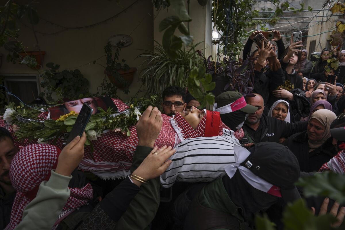Palestinian mourners carry the body of Omar Manaa during his funeral in the West Bank refugee camp of Deheishe near the city of Bethlehem, Monday, Dec. 5, 2022. Palestinian health officials say a 22-year-old Palestinian man has been killed by Israeli fire during a military raid in the occupied West Bank. The army said it opened fire after a crowd attacked soldiers with stones and firebombs. (AP Photo/Mahmoud Illean)