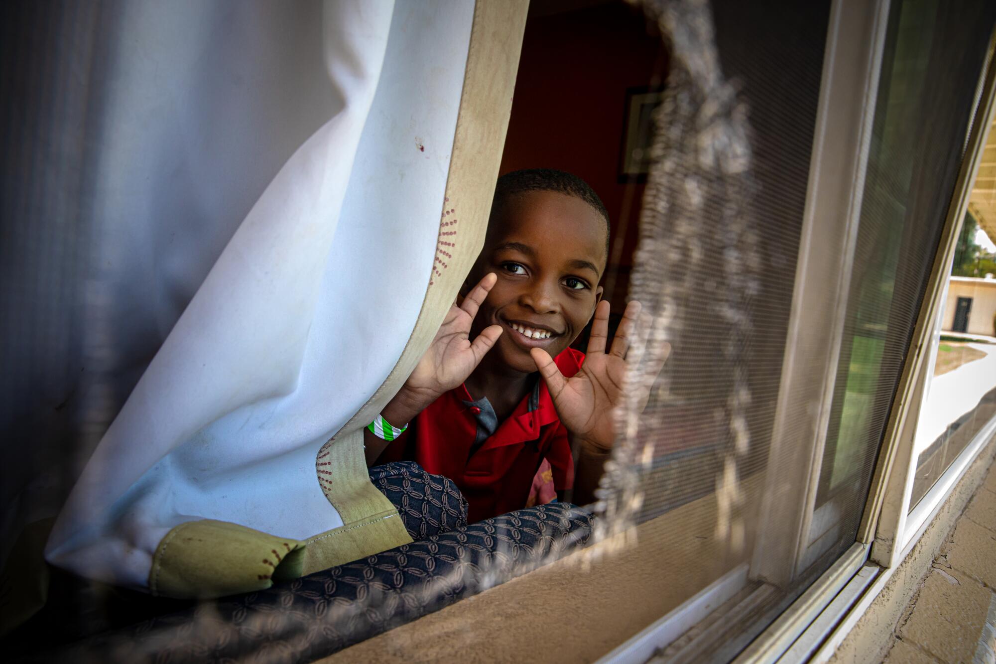 Rood Morancy Siverne, son of Haitian asylum seekers, peeks through a window at the shelter for newly arrived immigrants.