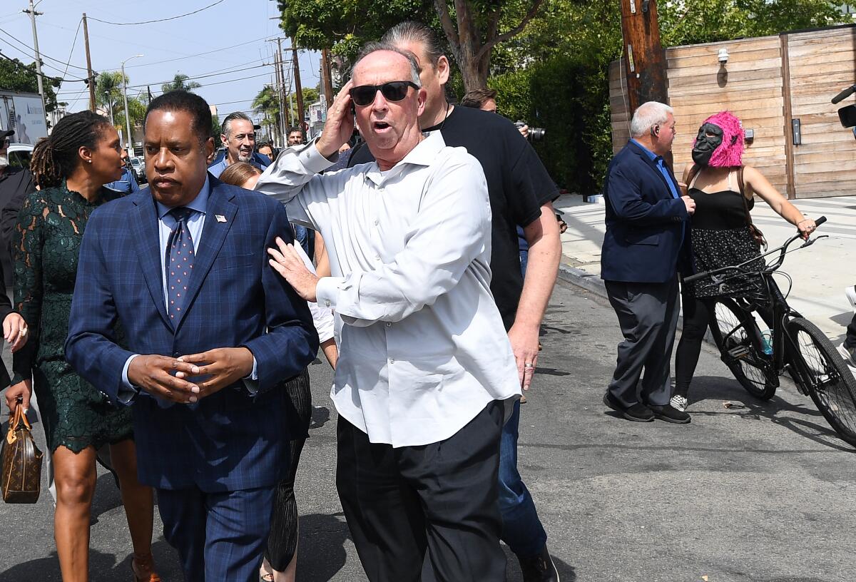 Republican gubernatorial candidate Larry Elder is escorted by a security guard 