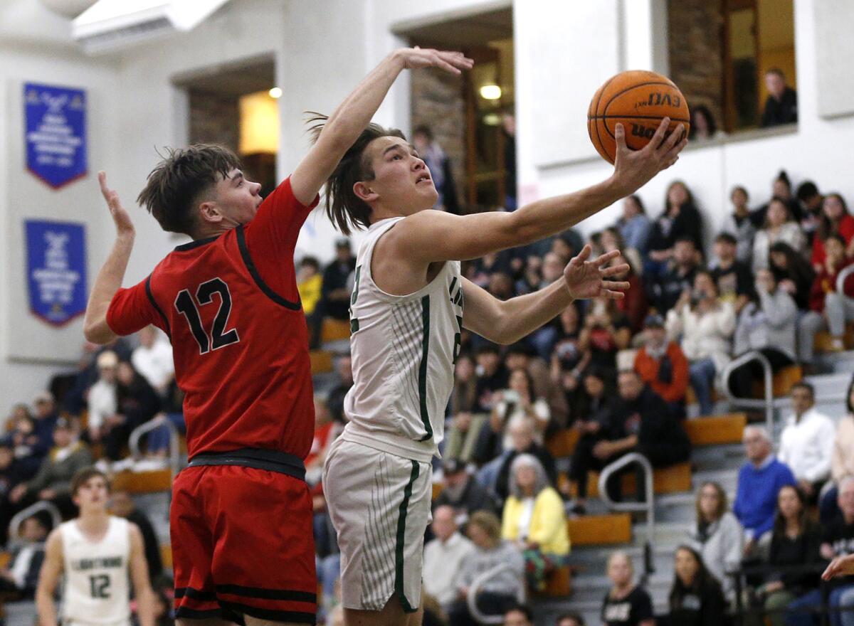 Sage Hill's Andrew Cobb (22) goes up and under for a layup past Whittier's Aaron Villescas (12) on Wednesday.