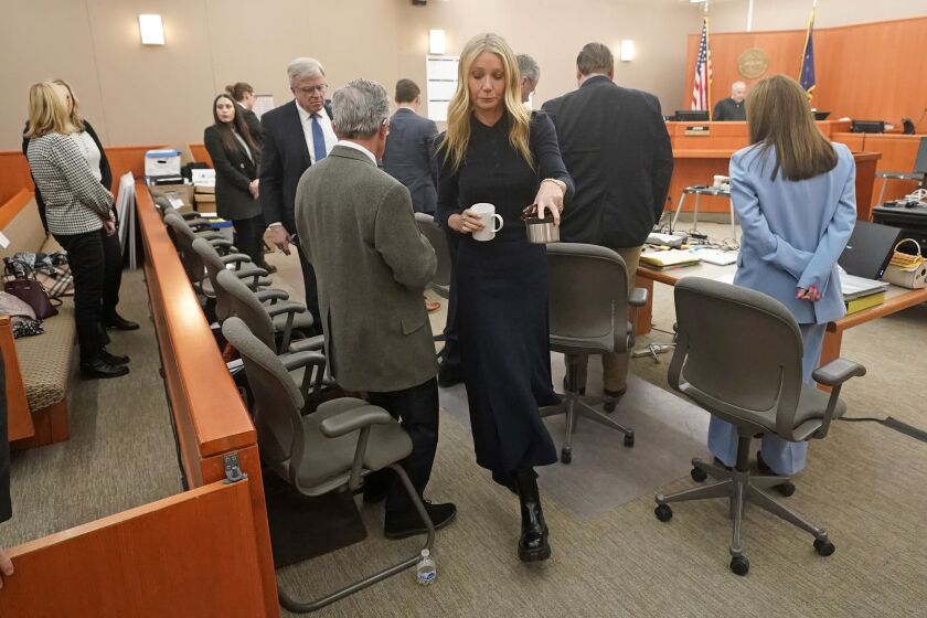 Gwyneth Paltrow carries two beverages as she walks past Terry Sanderson, the man suing her, after testifying in court on Friday, March 24, 2023, in Park City, Utah. Sanderson accuses her of crashing into him on a beginner run at Deer Valley Resort, leaving him with brain damage and four broken ribs. (AP Photo/Rick Bowmer, Pool)