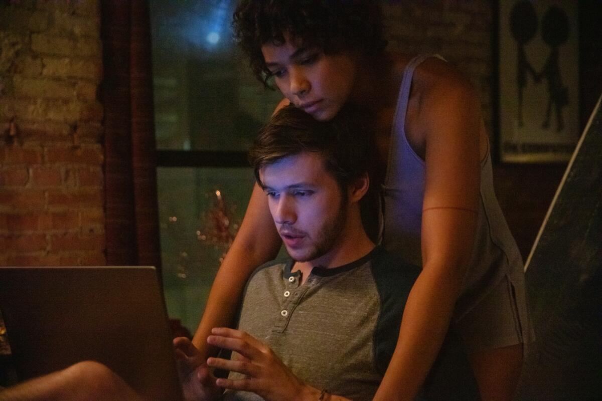Alexandra Shipp leans over Nick Robinson, who is on his laptop, in a scene from the film.