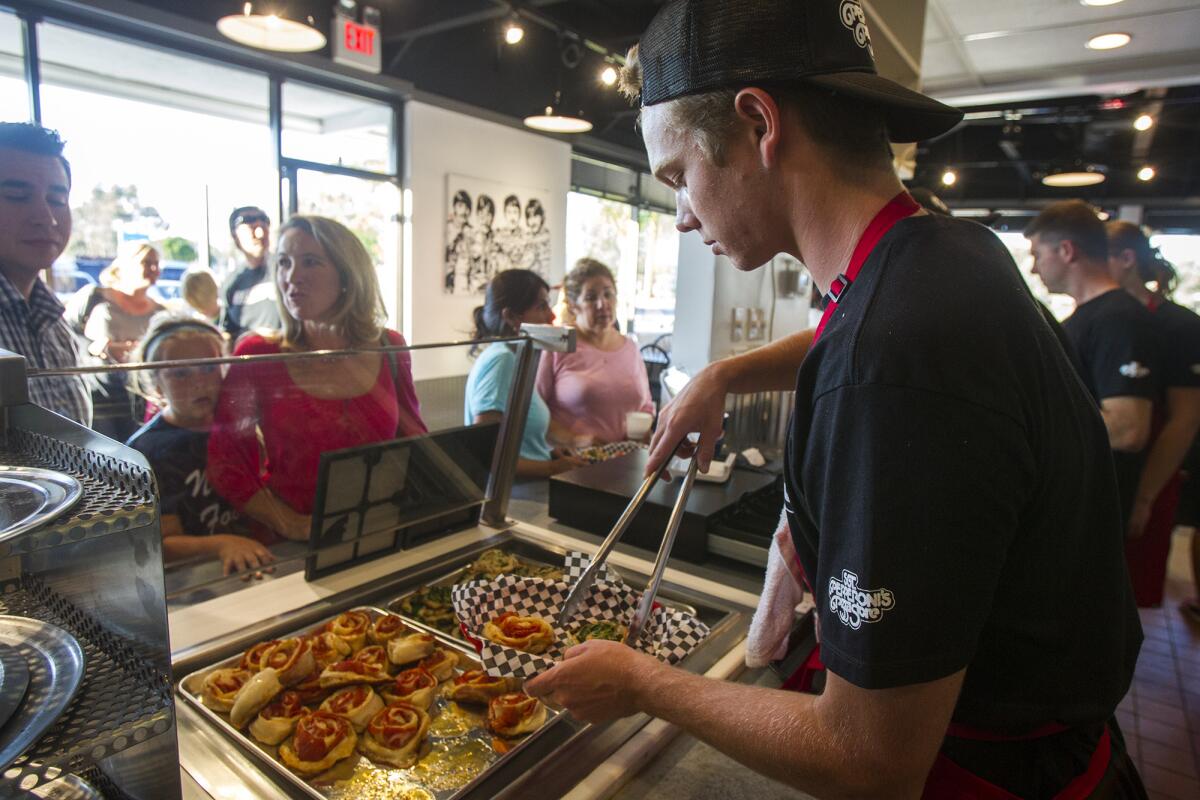 Jack Platner fills an order for pepperoni pin wheels during the grand reopening of Sgt. Pepperoni's Pizza Store on Friday.