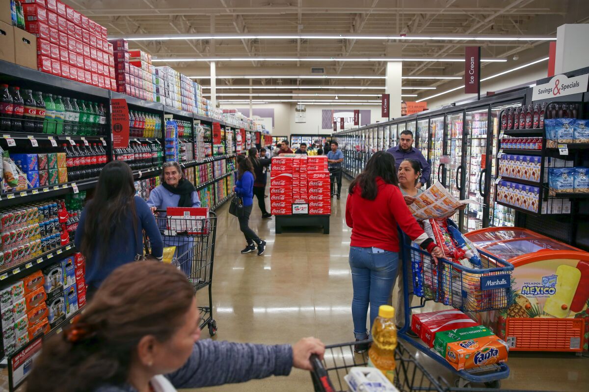 Shoppers push carts inside a Smart & Final soda aisle.