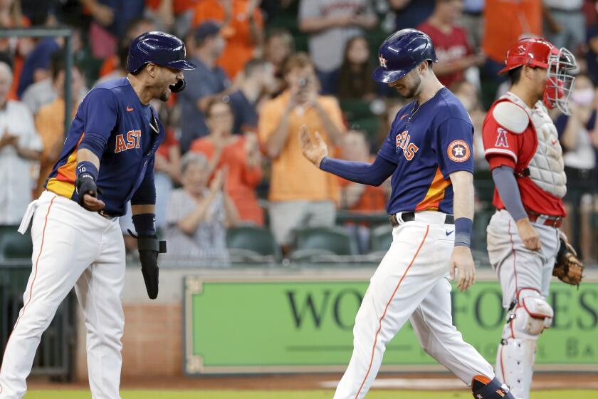 Houston Astros'' Yuli Gurriel, left, and Kyle Tucker, center, celebrate next to Los Angeles Angels catcher Kurt Suzuki, right, after they scored on a two-run home run by Tucker during the sixth inning of a baseball game Sunday, Sept. 12, 2021, in Houston. (AP Photo/Michael Wyke)