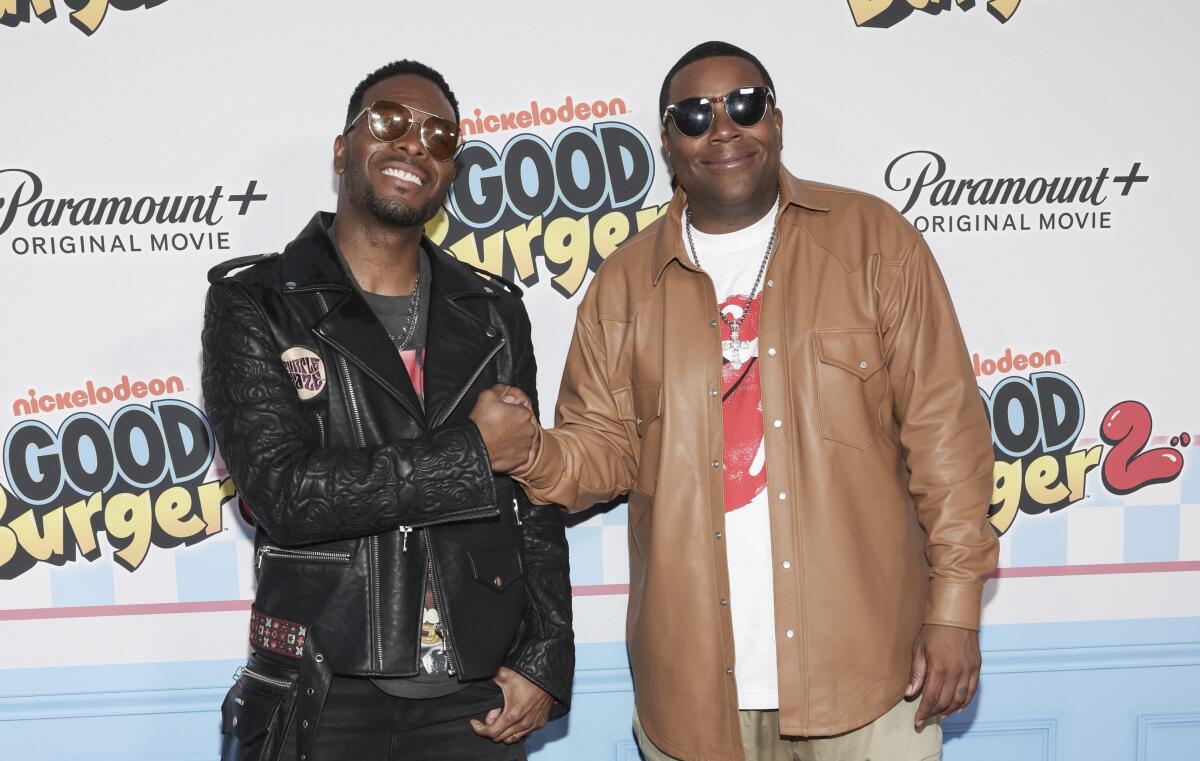 Kel Mitchell in a black leather jacket bumping fists with Kenan Thompson, clad in a brown shirt over a T-shirt