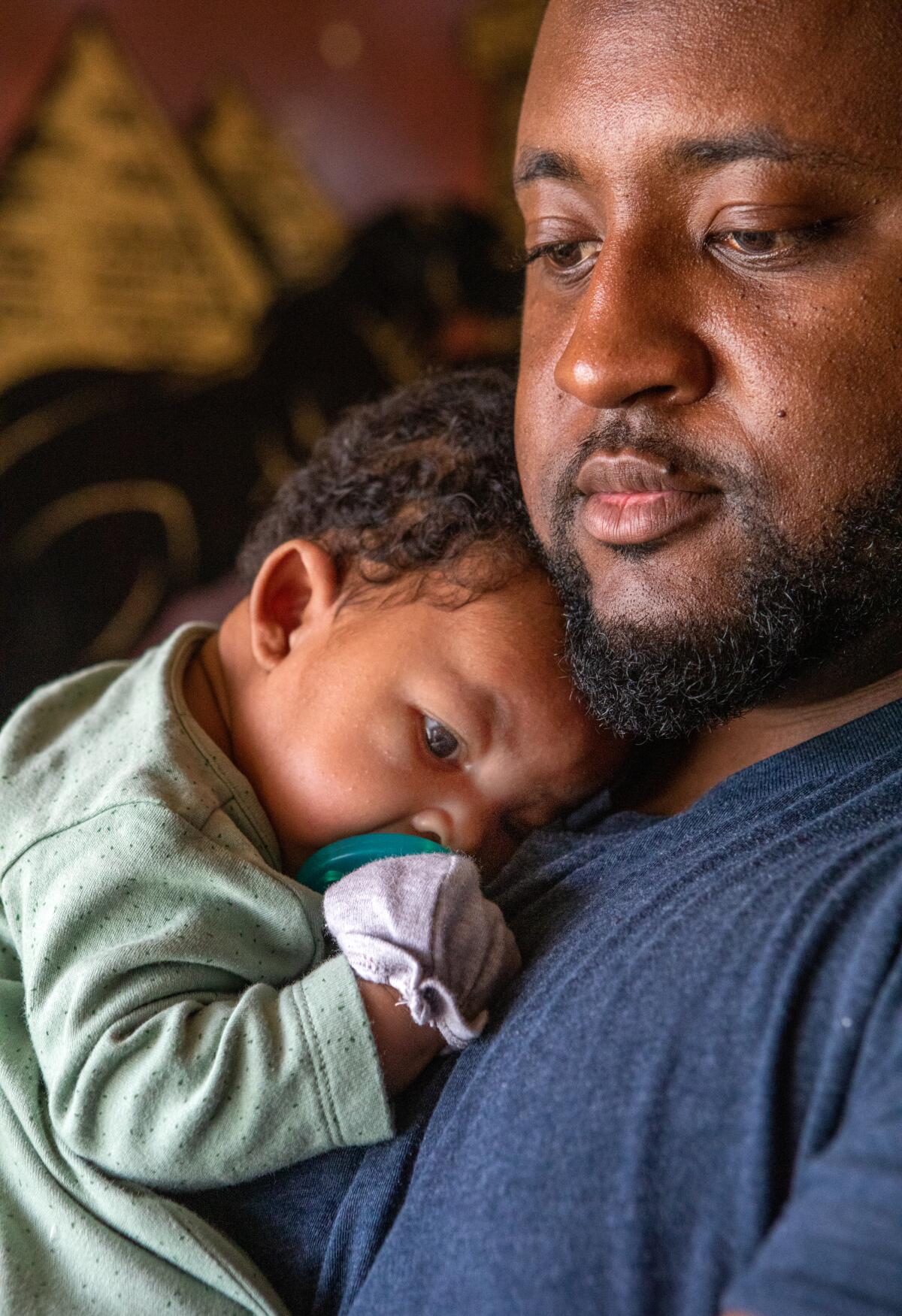 Danny Rollins holds his newborn, Braylen Rollins, in their home in Compton.