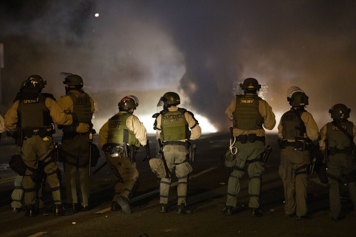 The backs of a line of people in uniforms.