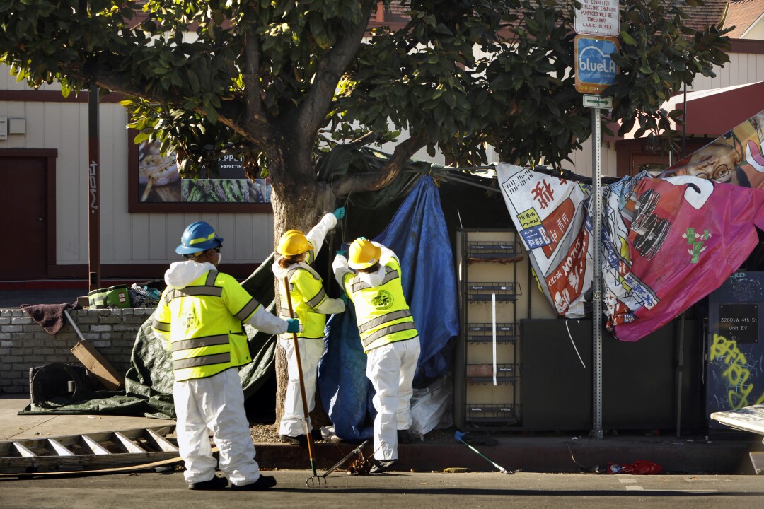 Los Angeles sanitation workers work take down a makeshift shelter