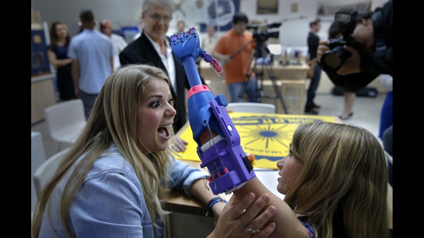 Nicole Lennox of Lakewood celebrates with her 7-year-old daughter, Faith, as she uses her new left hand made by a 3D printer.