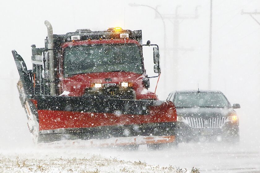 A South Dakota state snow plow clears a shoulder along Highway 50 on the north edge of Yankton, S.D., on Thursday, Dec. 15, 2022, as light snow swept by strong winds reduced visibility to a quarter-mile at times. Yankton is about 200 miles east of the Rosebud Sioux Reservation, which was battered by a mid-December snowstorm that left roads impassable. A 12-year-old asthmatic boy was among six people who died on the reservation during the storm. The tribe says all of the deaths could have been prevented were it not for systemic failures and a lack of timely help. (Kelly Hertz/Yankton Press & Dakotan via AP)
