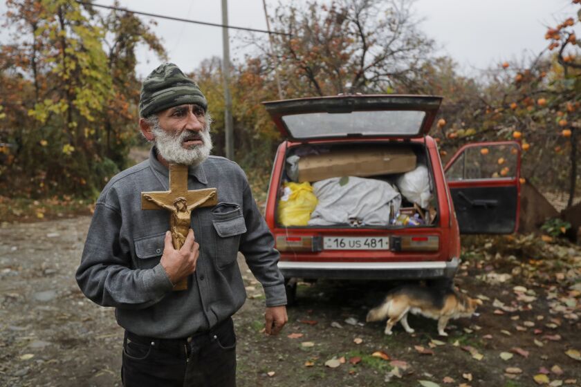 Nikolai Karapetyan reacts and presses the cross to his chest, with his car packed as he prepares to abandon his home in the village of Maraga, in the Martakert area, in the separatist region of Nagorno-Karabakh, Wednesday, Nov. 18, 2020. A Russia-brokered cease-fire to halt six weeks of fighting over Nagorno-Karabakh stipulated that Armenia turn over control of some areas it holds outside the separatist territory’s borders to Azerbaijan. (AP Photo/Sergei Grits)