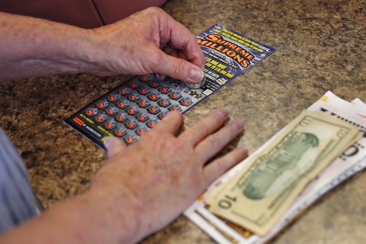 A woman scratches a lottery ticket on June 24 in Methuen, Mass.