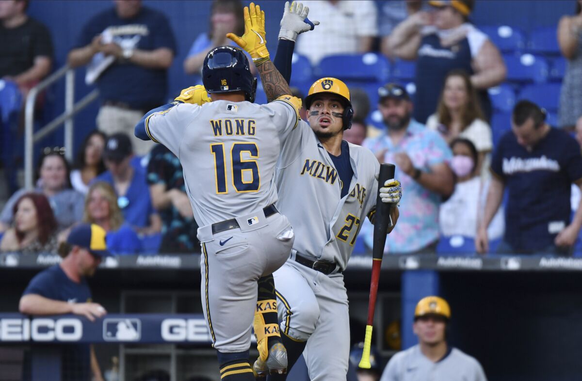 Milwaukee Brewers' Kolten Wong (16) celebrates his home run withWilly Adames (27) during the first inning of the team's baseball game against the Miami Marlins, Friday, May 13, 2022, in Miami. (AP Photo/Jim Rassol)