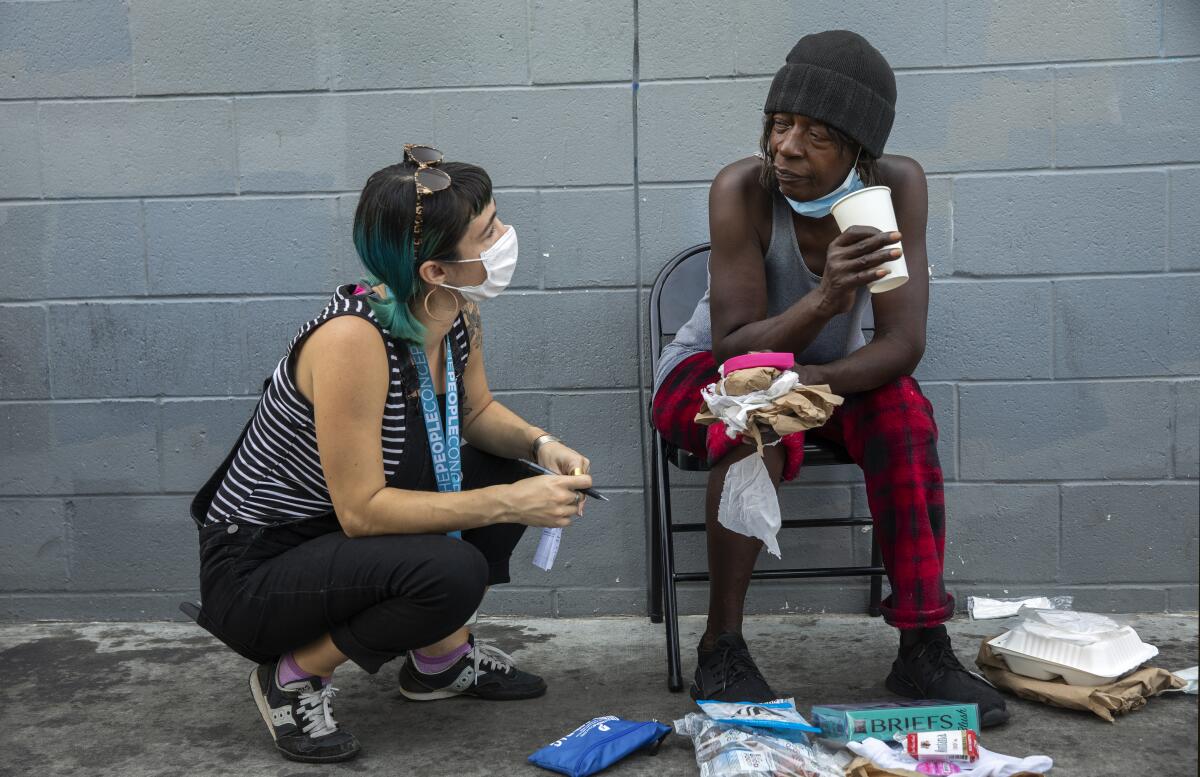 Ciara DeVozza talks with Janice Johnson as she waits for test results at a mobile clinic in downtown Los Angeles.