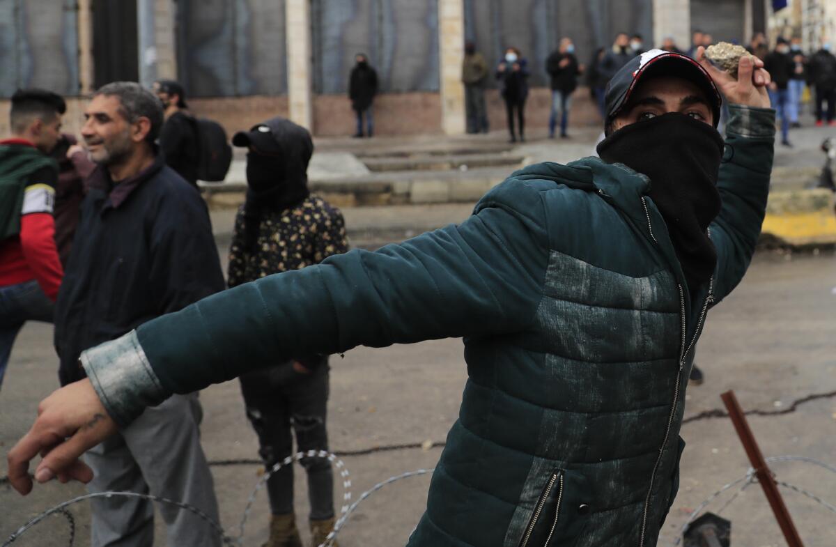 A protester throws a rock at riot police in Tripoli, Lebanon