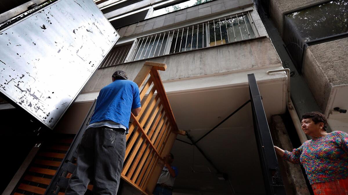 Movers haul away a bed frame from a condemned building in the popular Condesa neighborhood of Mexico City.