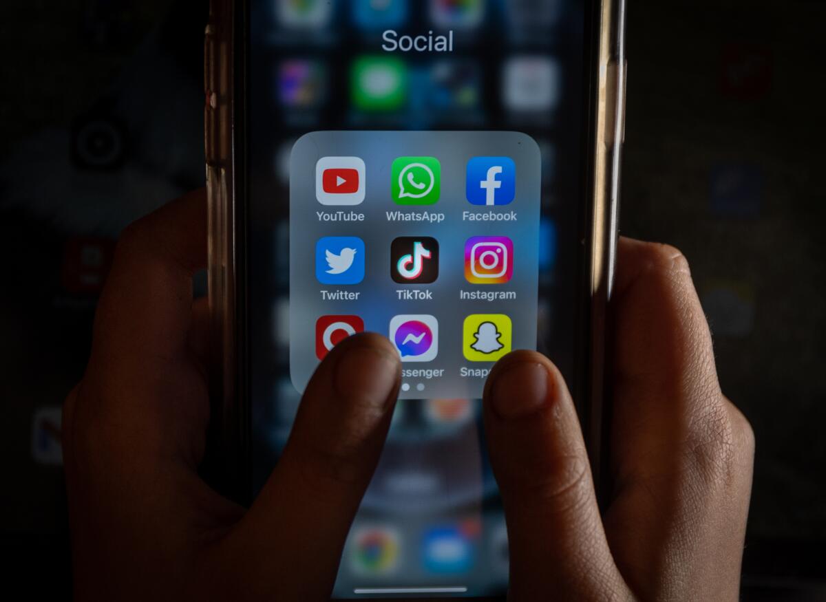 A cell phone shows social media apps on the home screen.