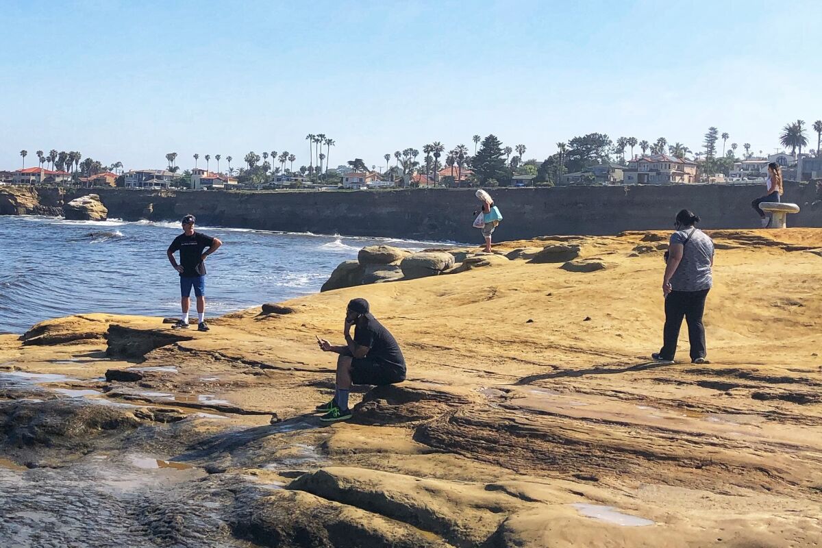 The Sunset Cliffs area of San Diego's Point Loma drew crowds over the weekend that worried officials, but returned to calm and distancing Monday morning. San Diego's beaches are open, with restrictions.