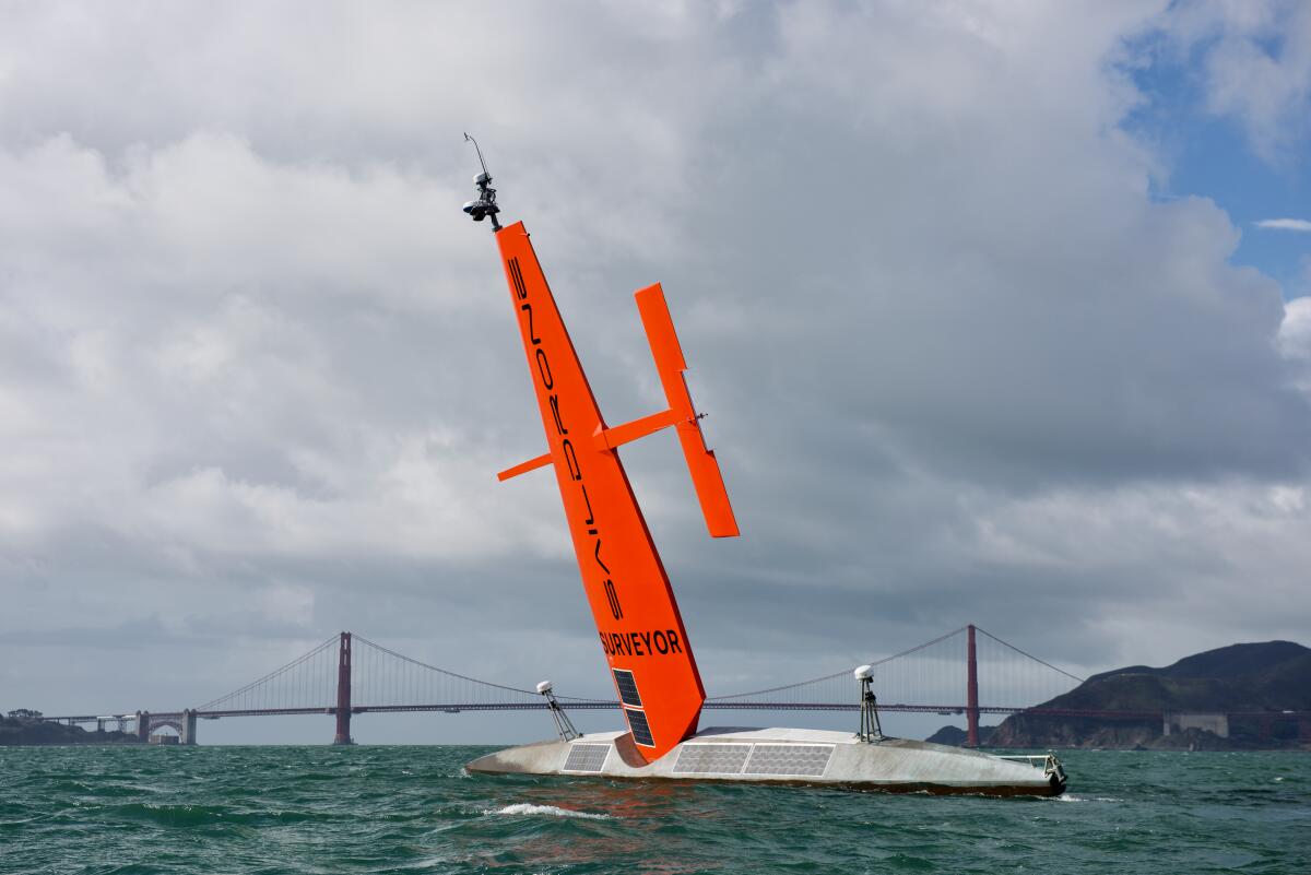 A watercraft is seen in the ocean; a bridge is in the background.