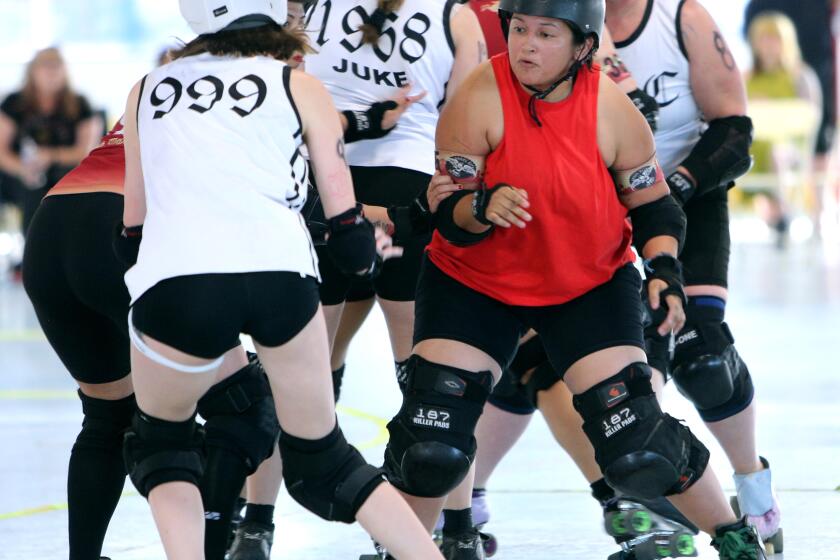 Roller derby Rocket Queens team blocker #185 Bash-n-Smash (Janeet (cq) Juarez), right, blocks the Misery Loves Company team jammer during the Fuego Latino Roller Derby competition at the Charles H. Wilson Park hockey rink in Torrance on Friday, July 8, 2023.