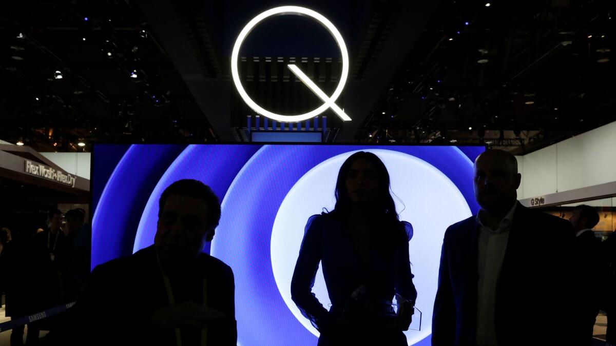 People stand in front of a QLED TV at the Samsung booth during CES International in Las Vegas.