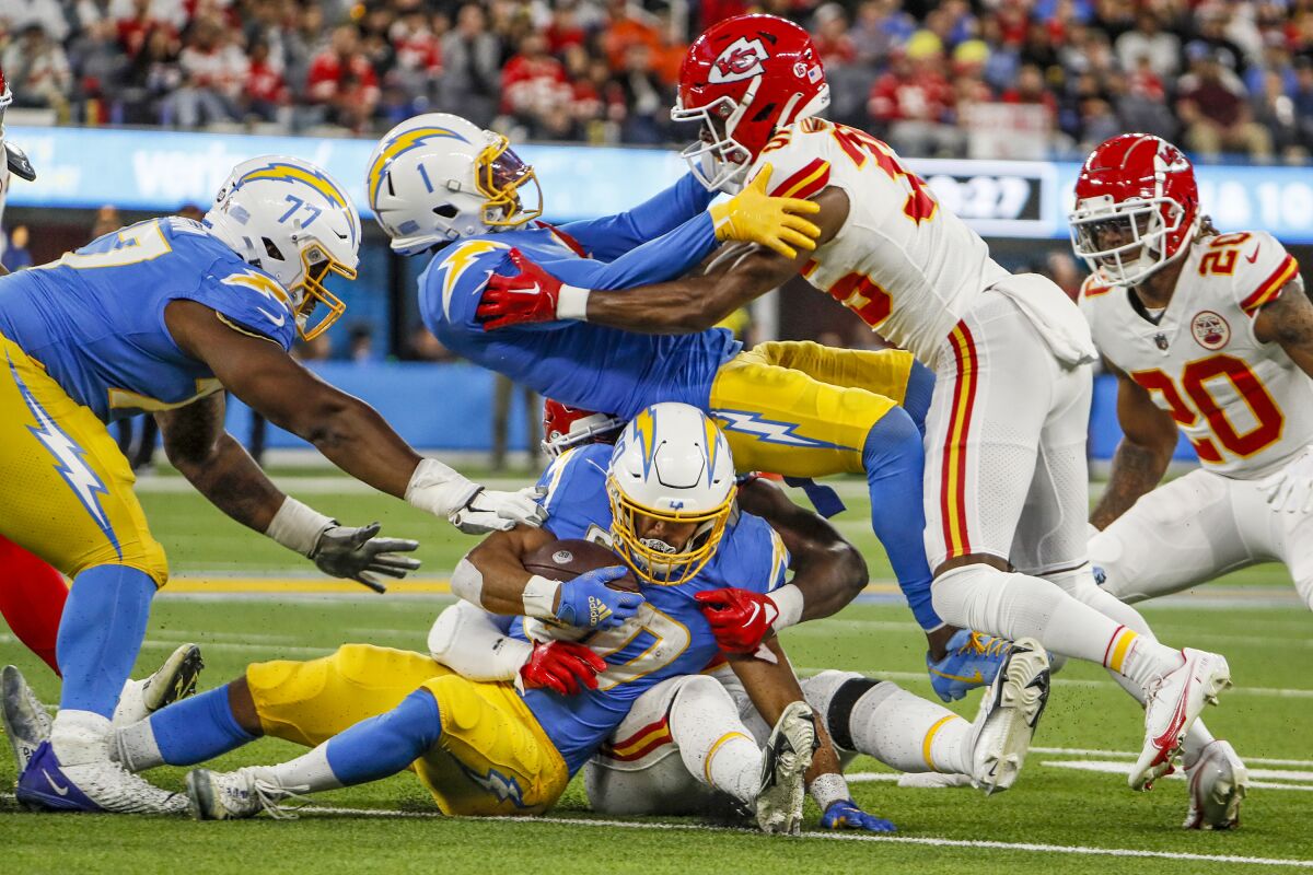 The Chargers' Austin Ekeler (30) is stopped as teammate DeAndre Carter (1) tries to hold off Chiefs corner Jaylen Watson.