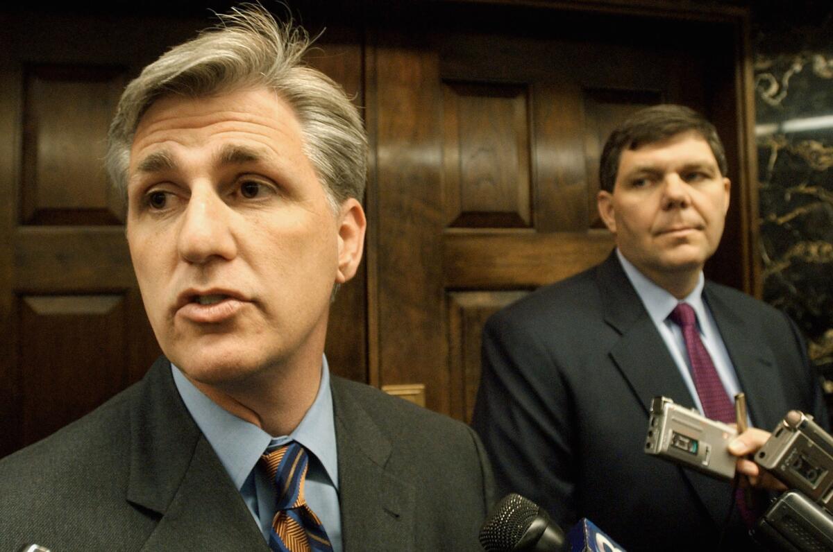 Two men in suits speak to reporters