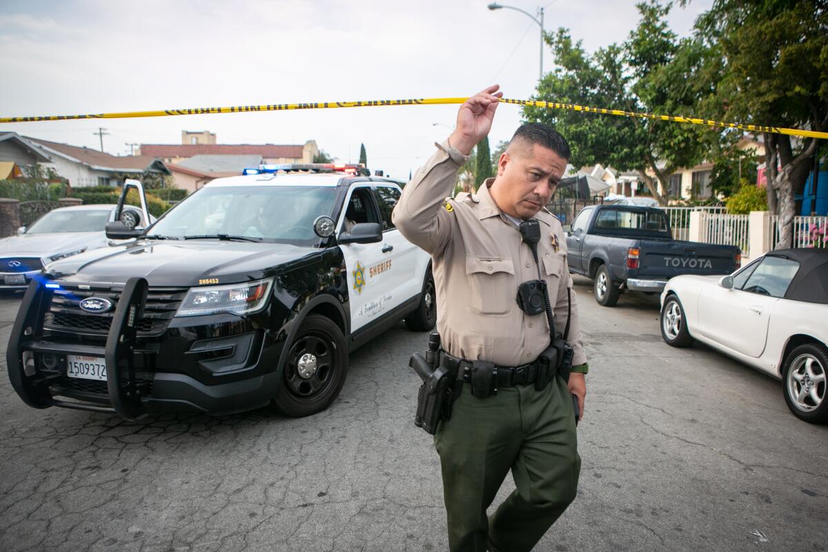 A sheriff's deputy ducks under crime scene tape in East Los Angeles