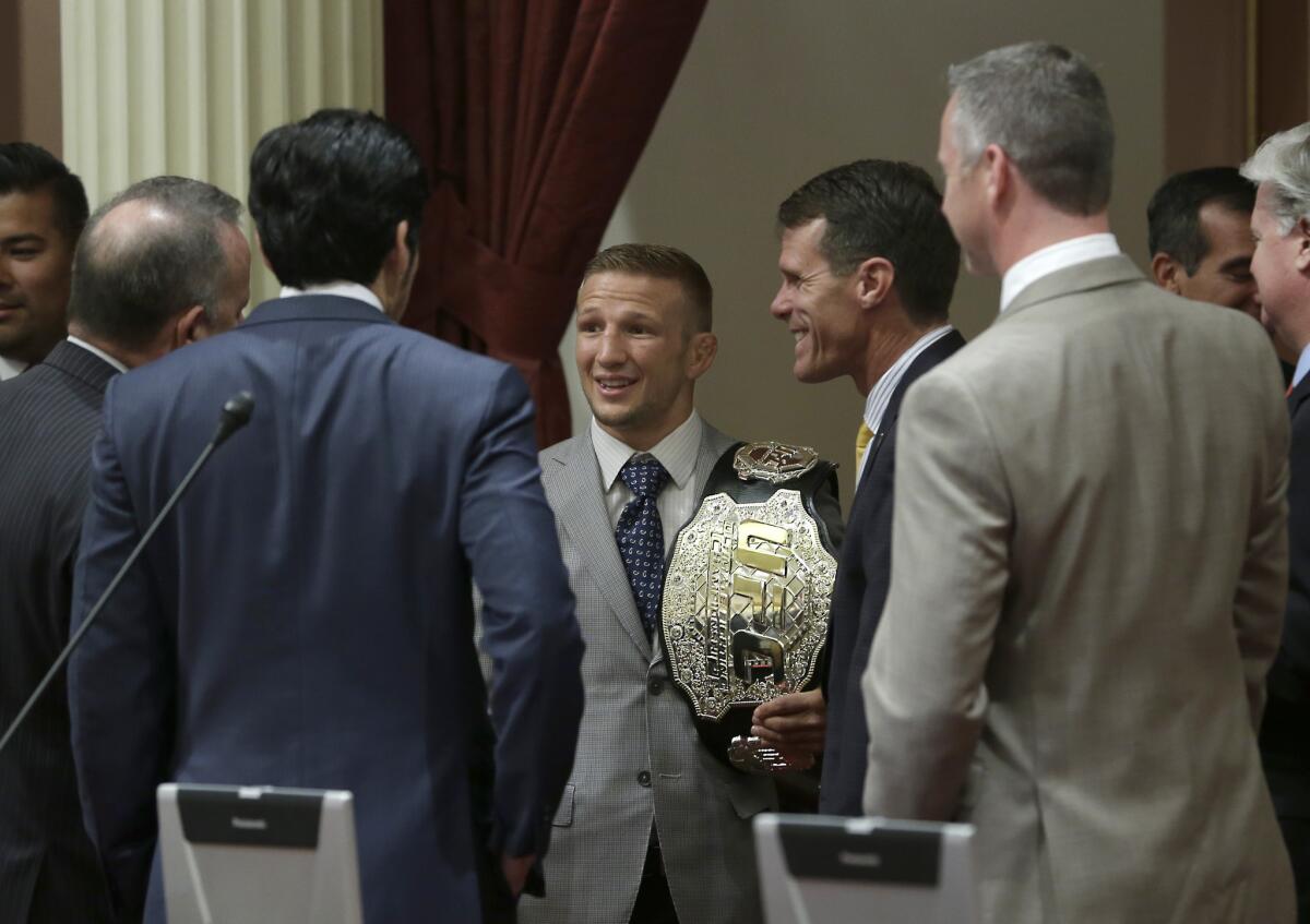 With his UFC belt over his shoulder, T.J. Dillashaw is greeted by members of the state Senate during a visit to the Capitol in Sacramento.