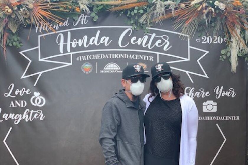 Wearing matching Ducks hats and surgical masks, Jayson Furusawa and Lynsey Koopman recently got "Hitched At Honda Center."
