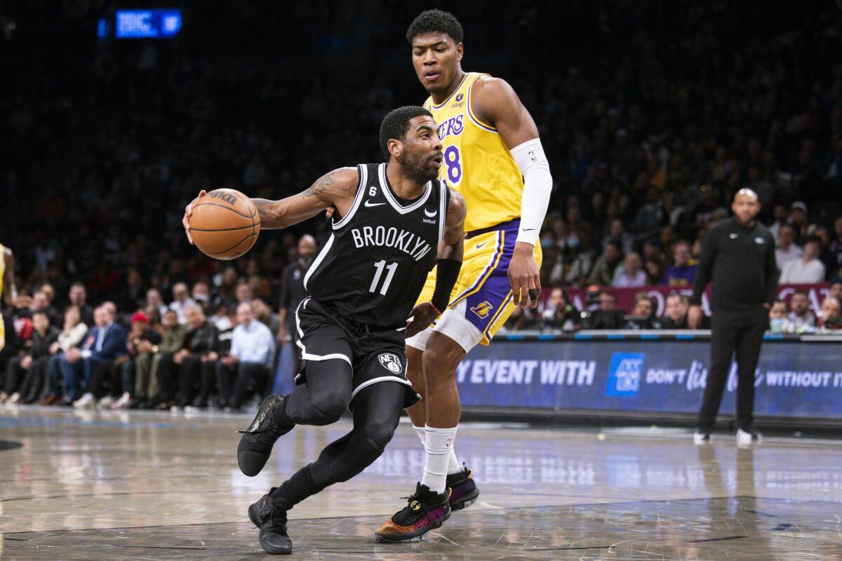 El base de los Nets de Brooklyn Kyrie Irving avanza hacia la canasta mientras lo defiende el alero de los Lakers
