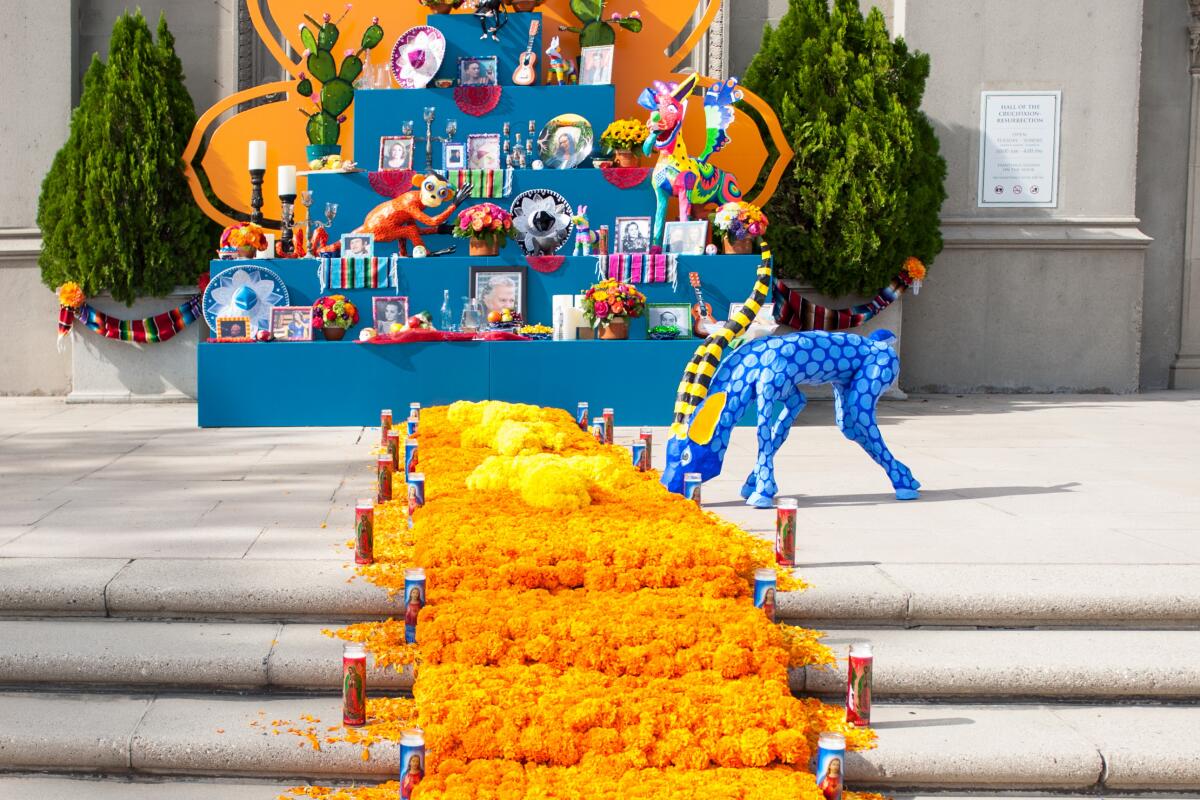 Orange marigolds create a path toward a decorated altar with a blue spirit animal to the side.