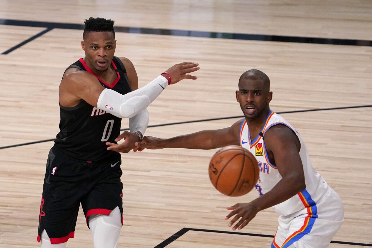 Rockets guard Russell Westbrook makes a pass under pressure from Thunder guard Chris Paul durina game Sept. 2, 2020.