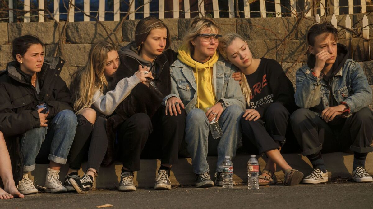 Grace Combs, 15, from left, Muriel Rowley, 15, Olivia Jacobson, 16, Emma Jacobson, 19, Anna Niebergall, 20, and Sally Niebergall, 16, comfort each other as the Jacobson sisters watch their home burn in Ventura.