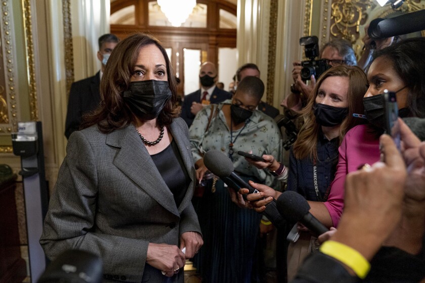 Vice President Kamala Harris wears a black mask and speaks to reporters