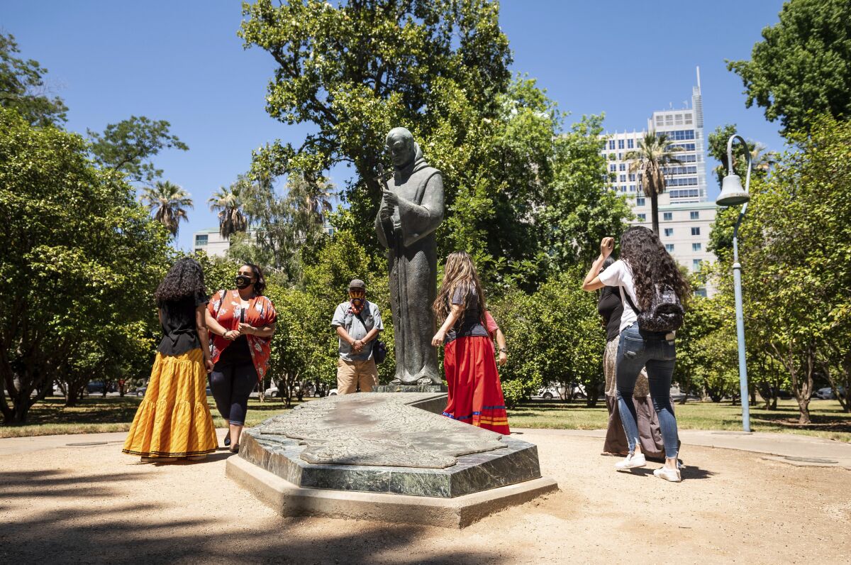 People gather near the Father Junipero Serra statue on the Capitol Park grounds in Sacramento.